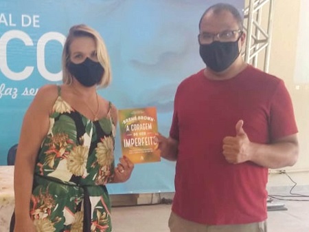 Luciana Boaretto com um livro ao lado do coach Claudio Pires Cardoso