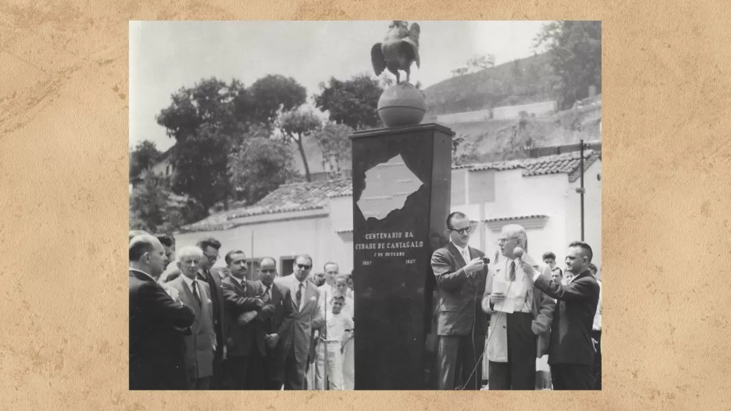 A solenidade de inauguração do Marco do Centenário da Cidade de Cantagalo. Do lado direito do Marco, o governador Miguel Couto Filho. Do lado do dr. Júlio Santos, o deputado federal Miguel Couto Filho. Do lado esquerdo, o dr. Júlio Veríssimo faz o discurso oficial, tendo, do seu lado direito, Dalvan Lima e, do lado esquerdo, Milton Loureiro, repórteres, respectivamente, do Governo Fluminense e do Grande Jornal Fluminense, transmitido pela rádio Tamoio, na parte da manhã. (Acervo Instituto Mão de Luva).